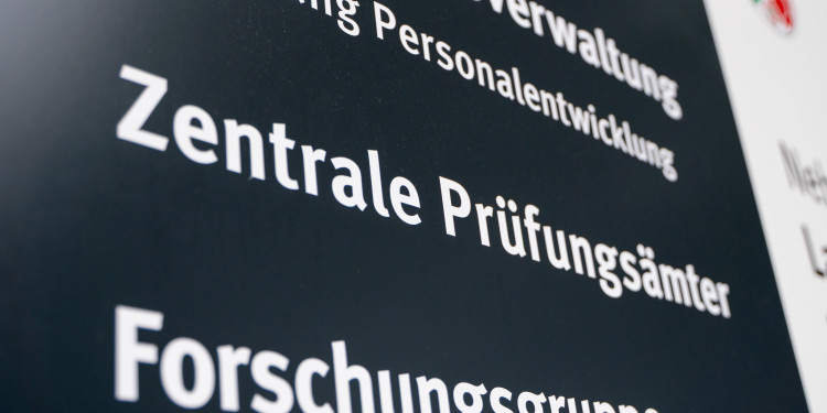 Das Bild zeigt ein Schild, das auf die zentralen Prüfungsämter der Uni hinweist.<address>&copy; Uni MS – Linus Peikenkamp</address>