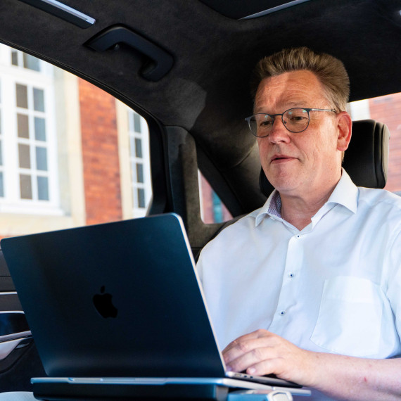 The photo shows the Rector, sitting and working in the back of a car.<address>&copy; Uni MS - Linus Peikenkamp</address>