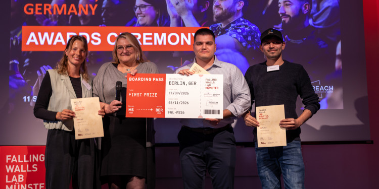 Das Bild zeigt vier Personen auf einer Bühne. Drei von ihnen halten Siegerurkunden in den Händen.<address>&copy; Uni MS - Nike Gais</address>