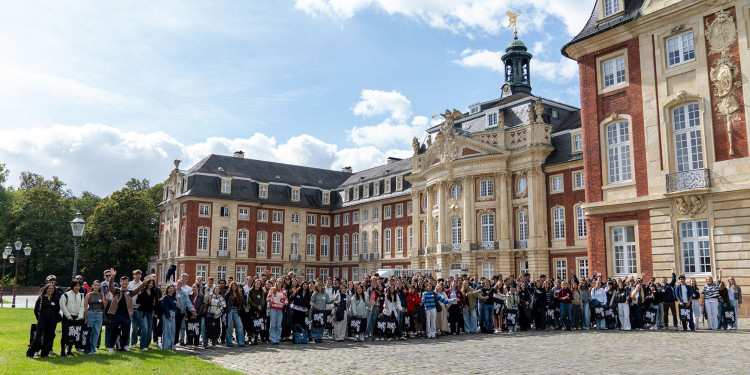 Eine Gruppe von rund 200 jungen Personen steht vor dem Schloss der Uni Münster.<address>&copy; Uni MS - Johannes Wulf</address>