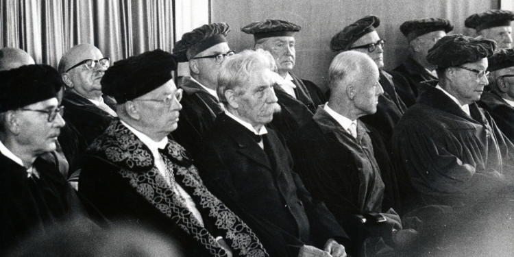 Schwarz-Weiß-Aufnahme von der Feierstunde: Das Bild zeigt die Personen in der ersten und zweiten Reihe von der Seite, wie sie der Veranstaltung folgen.<address>&copy; Universitätsarchiv, Bestand 68 Nr. 9603</address>