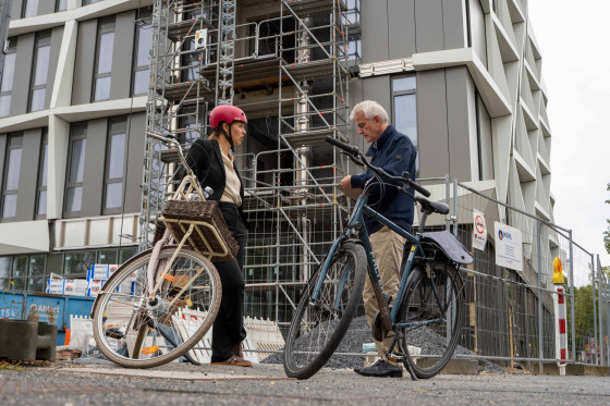 Rektorin Prof. Dr. Susanne Menzel-Riedl und Pressesprecher Norbert Robers haben ihre Räder vor der Baustelle am „Centre for Mathematics Münster“ geparkt und unterhalten sich.<address>&copy; Uni MS - Johannes Wulf</address>