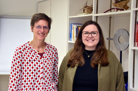 Prof. Dr. Stefanie van Ophuysen (links) und Rebecca Meier stehen in einem Seminarraum und schauen freundlich in die Kamera.<address>&copy; Uni MS - Julia Harth</address>
