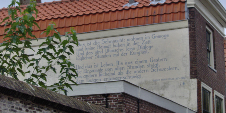 Zu sehen ist eine Hauswand im niederländischen Leiden, auf dem Zeilen eines Rilke-Gedichts zu lesen sind.<address>&copy; Wikimedia | Tubantia</address>